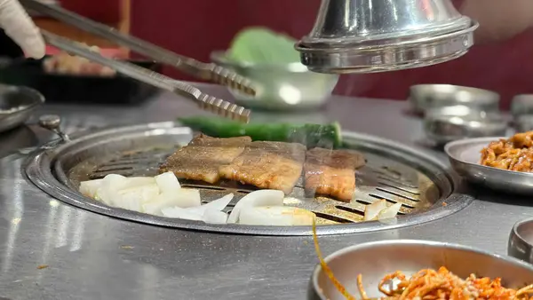 Özel bir sosta marine edilmiş domuz eti, Güney Kore 'de ünlü bir barbekü restoranı olan Saemaeul' un ızgarasında ızgara..