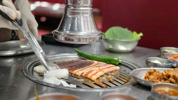 Özel bir sosta marine edilmiş domuz eti, Güney Kore 'de ünlü bir barbekü restoranı olan Saemaeul' un ızgarasında ızgara..