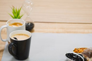 Tahta bir masada bir fincan kahve ve tatlı.