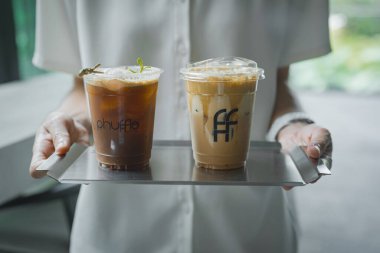 Kadın ellerinde buzlu kahve bardakları.