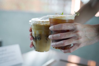 Kafedeki kadınların ellerinde bir fincan buzlu kahve