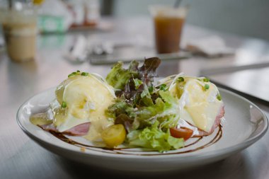 Yumurtalı Benedict sandviçi, yanında haşlanmış yumurta ve restoranda jambon..