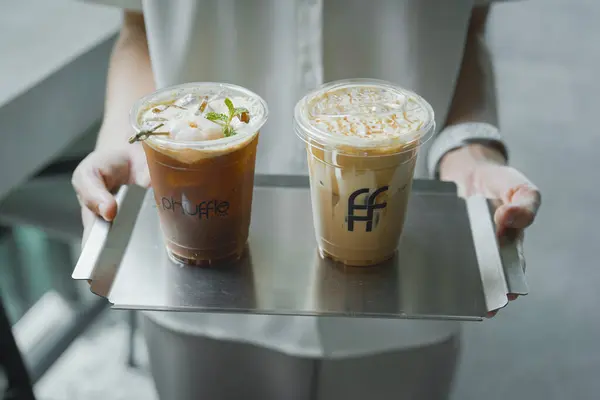 Kadın ellerinde buzlu kahve bardakları.