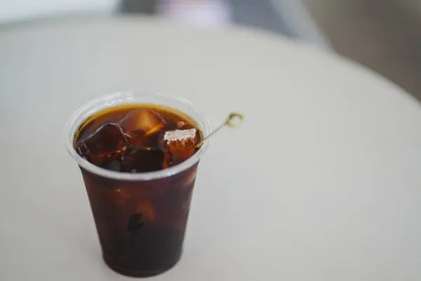 Kahve dükkanındaki beyaz masanın üzerine bir bardak buzlu bal americano kopyala ve kavramı ayır..