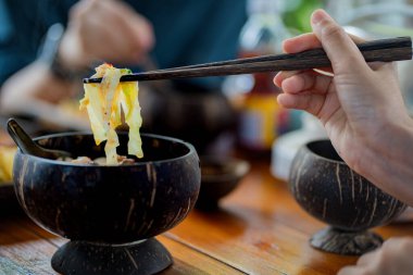 Nodles restoranındaki tahtadan kasede lezzetli erişte ve et yiyen isimsiz bir kadın..