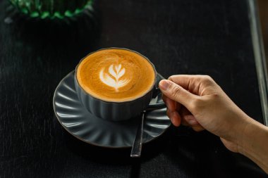 Yakın plan bir kahve fincanı ile masa kafesinin arka planında yazı için yeri olan bir el.