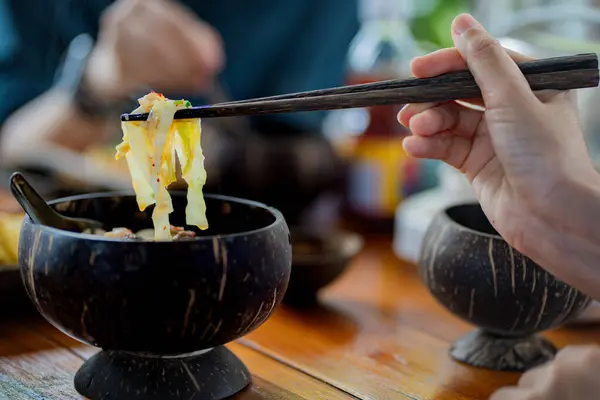 Nodles restoranındaki tahtadan kasede lezzetli erişte ve et yiyen isimsiz bir kadın..