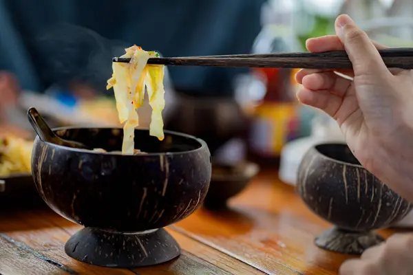 Nodles restoranındaki tahtadan kasede lezzetli erişte ve et yiyen isimsiz bir kadın..