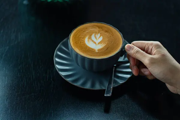 Yakın plan bir kahve fincanı ile masa kafesinin arka planında yazı için yeri olan bir el.