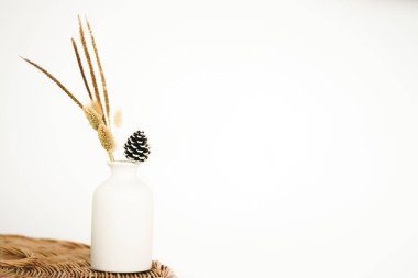 Oturma odasında beyaz arkaplanı olan dokuma masadaki çiçeğin seçici vazosunu kapat, boşluk konseptini kopyala.