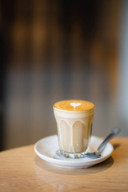  hot latte coffee with latte art in a white cup on wooden table, copy space concept.