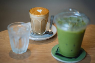 Kahve dükkanındaki ahşap masada, kahve bardağında latte sanatıyla seçici bir odak noktası. Uzay konseptini kopyala..