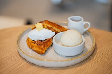 Bir tabak Belçika waffle tatlısı. Dondurma ve ahşap masada böğürtlenlerle süslenmiş..
