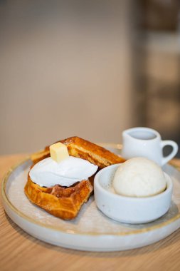 Bir tabak Belçika waffle tatlısı. Dondurma ve ahşap masada böğürtlenlerle süslenmiş..