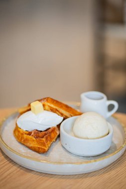 Bir tabak Belçika waffle tatlısı. Dondurma ve ahşap masada böğürtlenlerle süslenmiş..