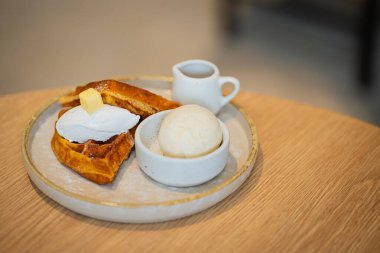 Bir tabak Belçika waffle tatlısı. Dondurma ve ahşap masada böğürtlenlerle süslenmiş..