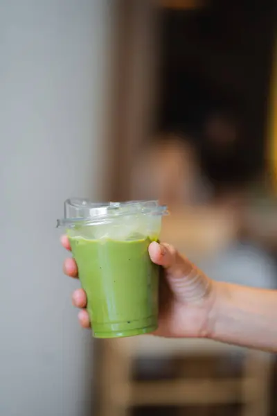 Kafe 'deki masada elinde buzlu kibrit latte tutan bir kadın..