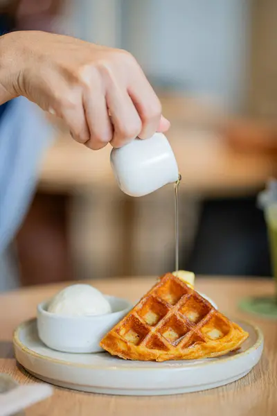 Kafede lezzetli waffle ve dondurma yiyen bir kadın.