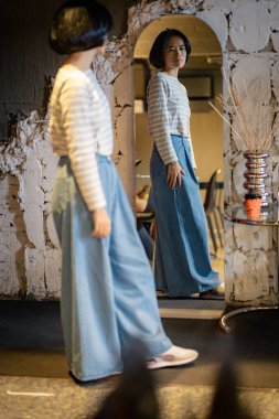 Kazaklı, kendine güvenen genç ve güzel bir kadın ve aynaya bakan kot pantolon kendisiyle gurur duyuyor.