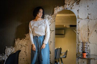 Taş duvarın yanında kemerli Asyalı kadın.