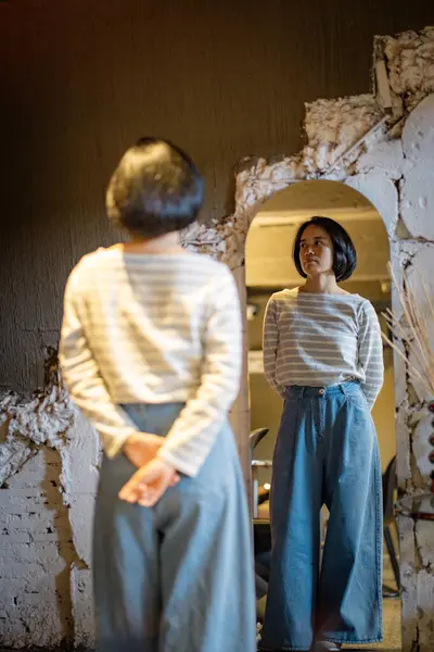 Kazaklı, kendine güvenen genç ve güzel bir kadın ve aynaya bakan kot pantolon kendisiyle gurur duyuyor.