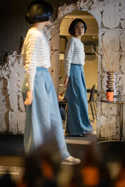 Kazaklı, kendine güvenen genç ve güzel bir kadın ve aynaya bakan kot pantolon kendisiyle gurur duyuyor.