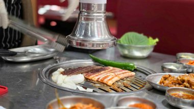 Özel bir sosta marine edilmiş domuz eti, Güney Kore 'de ünlü bir barbekü restoranı olan Saemaeul' un ızgarasında ızgara..