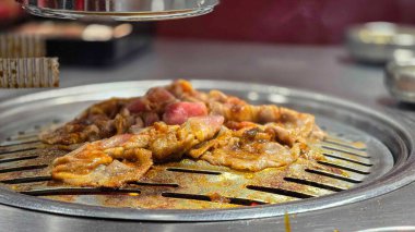 Özel bir sosta marine edilmiş domuz eti, Güney Kore 'de ünlü bir barbekü restoranı olan Saemaeul' un ızgarasında ızgara..