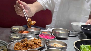 Asyalı aşçı masada yemek pişiriyor.