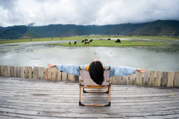 Mutlu Asyalı kadın gölde dinleniyor ve doğanın tadını çıkarıyor. Kaygısız yetişkin kız stresten ve şehir hayatından kopuk hissediyor.