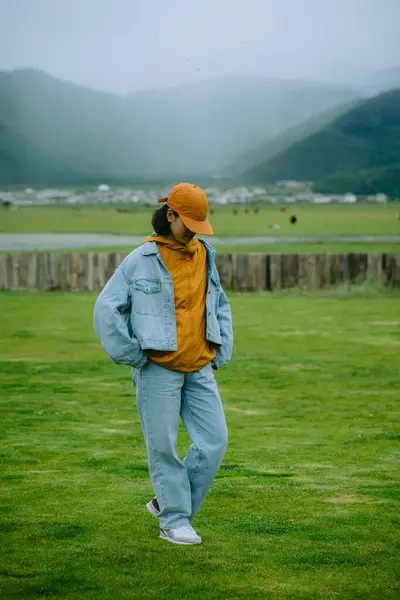 Manzaralı insanlar, kot ceketli ve pantolonlu genç bir kız seyahat ediyor ve güzel doğada dinleniyor. Özgür hissetmek ve her şeyden uzaklaşmak..