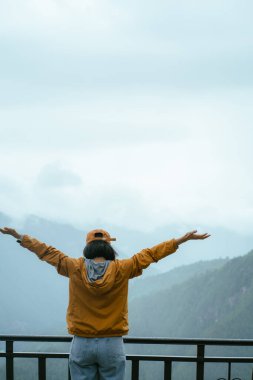 Genç bir kadın dağın tepesinde arka manzarada 