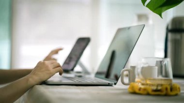 Evdeki oturma odasında akıllı telefon ve dizüstü bilgisayar kullanan kadınların yakın görüntüsü.