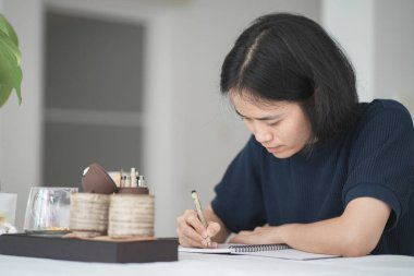 Güzel Asyalı kadın deftere yazıyor.  