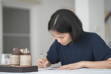 Güzel Asyalı kadın deftere yazıyor.  