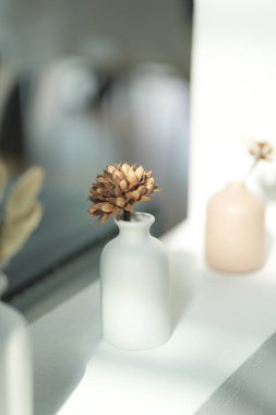 Beyaz seramik vazolar, kurumuş dallar ve modern iç mekanlarda dekoratif elementler.