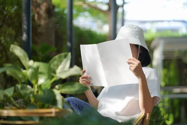Kafedeki masada kitap okuyan genç Asyalı kadın.