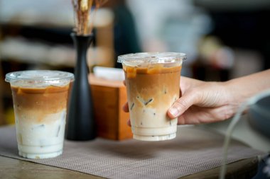 Elinde bir paket buzlu kahve tutan bir kadın.