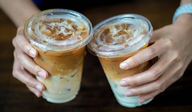 Kadın eli sütlü iki buzlu kahve tutuyor.