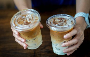 Kadın eli sütlü iki buzlu kahve tutuyor.