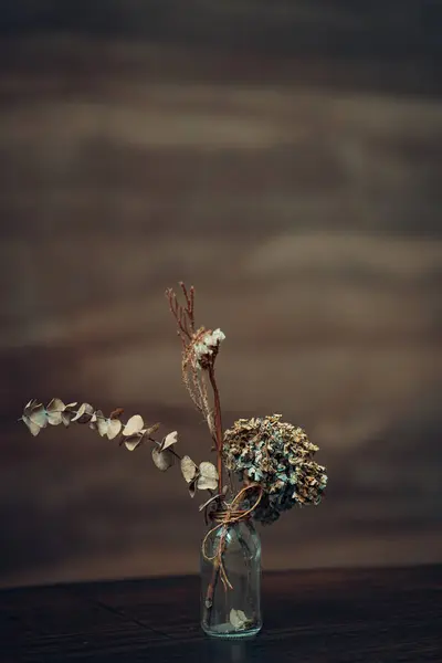 Ahşap masada cam kavanozda kurutulmuş bir buket çiçek. 