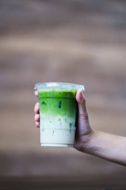 Elinde yeşil kibrit çayı tutan bir kadın.