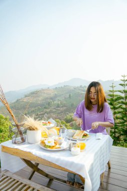 Kahvaltı masası olan mutlu bir kadın ve güzel bir dağ manzarası geçmişi olan, manzara konsepti olan insanlar..