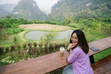 Dağların arkasında bir fincan kahvesi olan genç bir kız. 