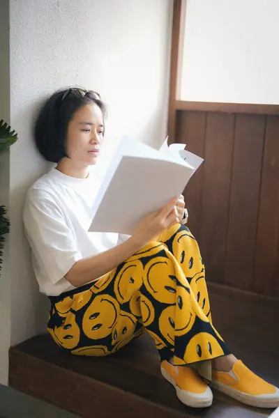 Kafede kitap okuyan güzel Asyalı bir kadın. 