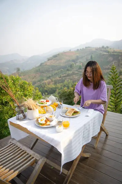Kahvaltı masası olan mutlu bir kadın ve güzel bir dağ manzarası geçmişi olan, manzara konsepti olan insanlar..