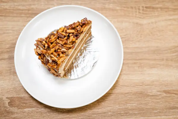 Karamelli bademli şekerleme. Kahverengi iğne kahveli kek, yukarıdan ahşap bir masada ayrı bir konteynırda.