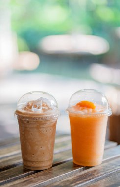 Bir bardak buzlu kahve frappe ve buzlu meyve frappe yaz terasında bir kafenin ahşap masa üzerinde, menü fotoğrafçılığı.