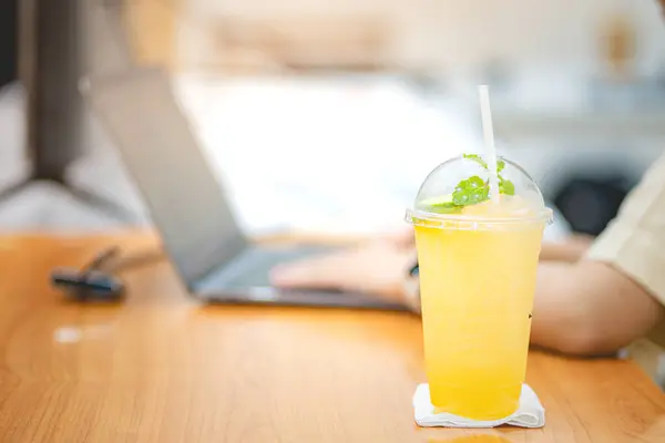 Ofisteki masada dizüstü bilgisayarlı bir bardak buzlu meyve suyu kapağı. Çalışma alanı kavramı..