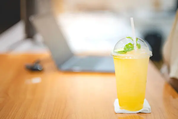 Ofisteki masada dizüstü bilgisayarlı bir bardak buzlu meyve suyu kapağı. Çalışma alanı kavramı..